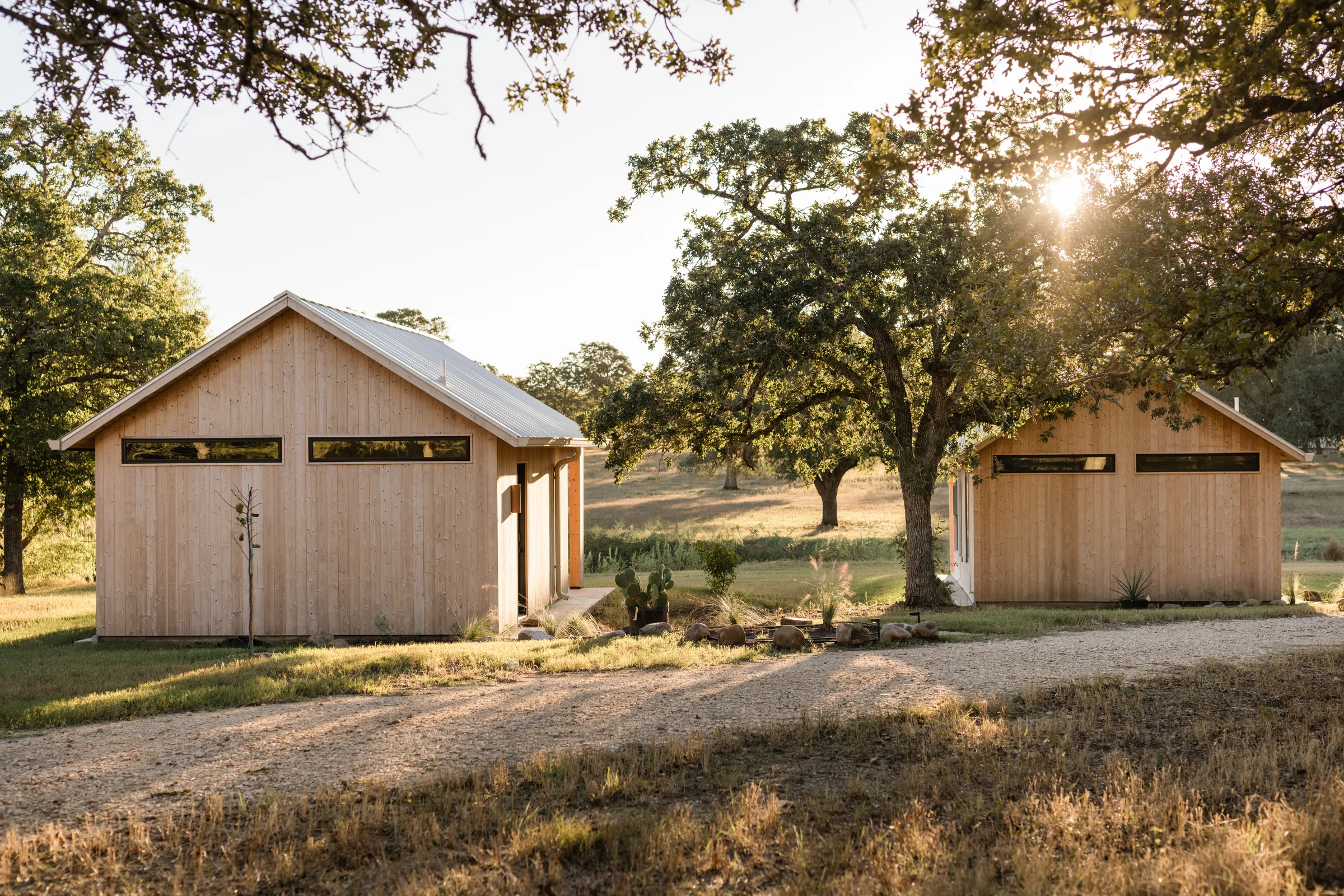 Two Serana cabins along a gravel path in warm evening light