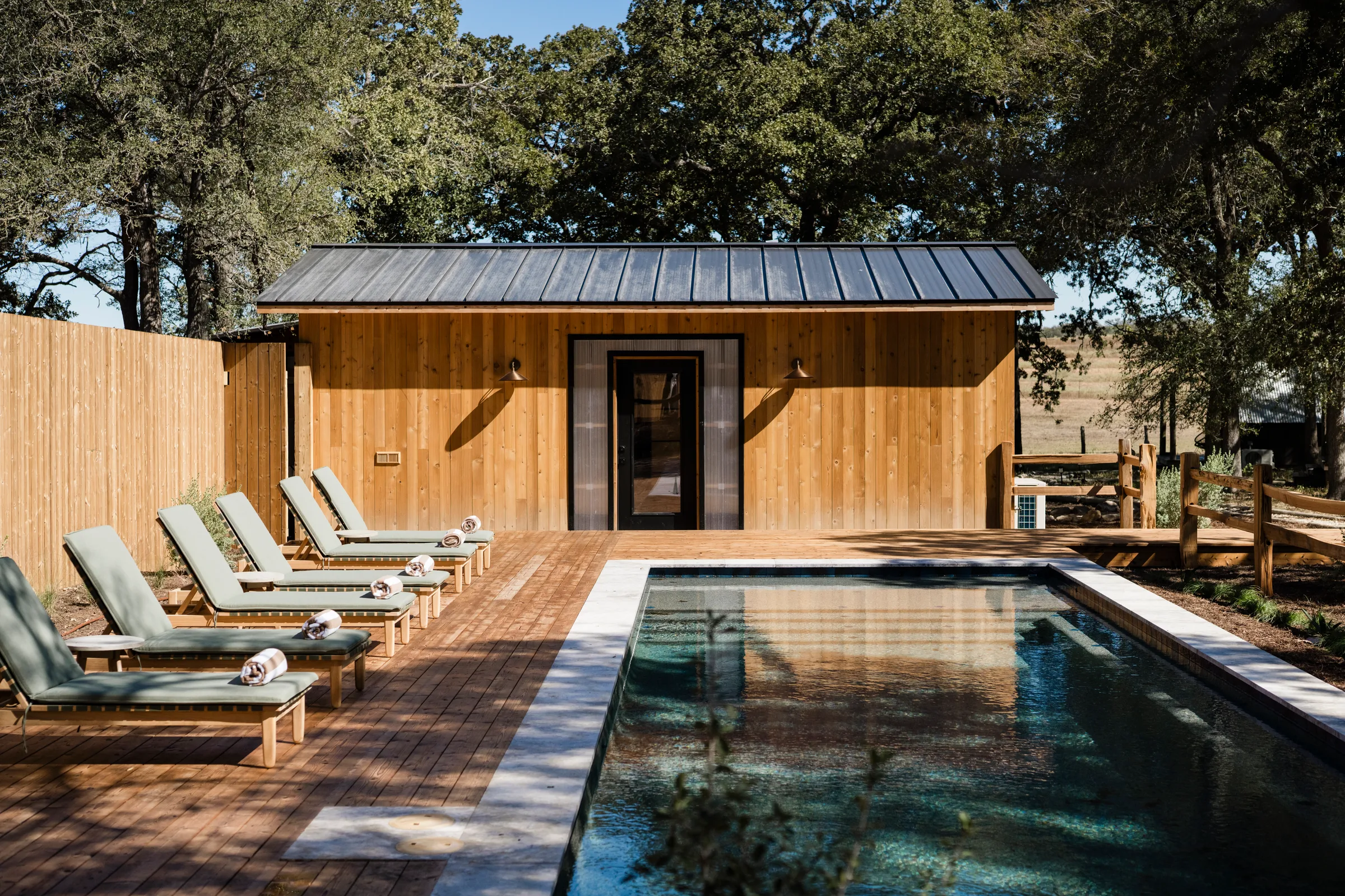 Serana pool house loungers beneath oak trees