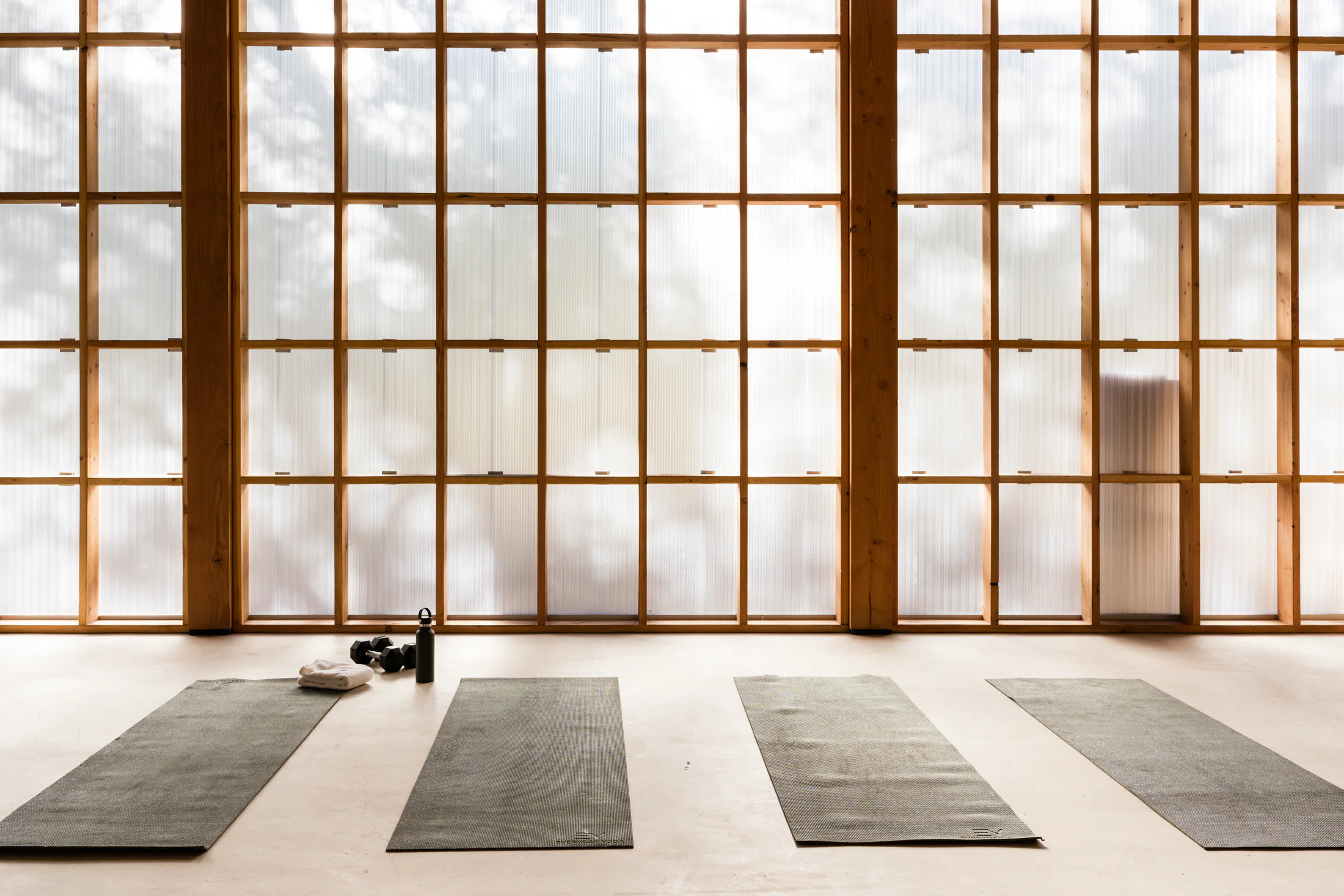 Serana fitness studio yoga mats beside wood-framed windows